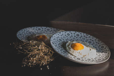 Homemade meal, Organic tasty cooked eggs for healthy breakfast on wood dark background and flowers in a vintage artistic composition. Simple food composition.の写真素材