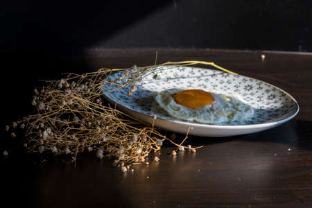Homemade meal, Organic tasty cooked eggs for healthy breakfast on wood dark background and flowers in a vintage artistic composition. Simple food composition.の写真素材