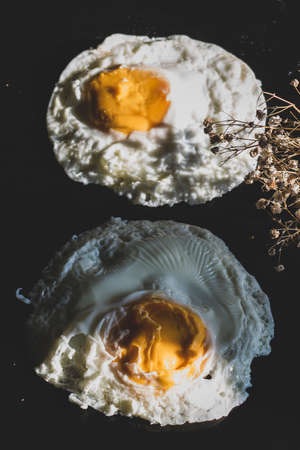 Homemade meal, Organic tasty cooked eggs for healthy breakfast on wood dark background and flowers in a vintage artistic composition. Simple food composition.の写真素材