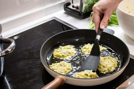 Young charming Swedish woman cooking at home in her kitchen, preparing healthy mediterranean food...