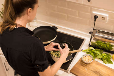 Young charming Swedish woman cooking at home in her kitchen, preparing healthy mediterranean food...