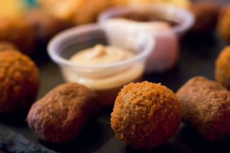 crispy fried chicken nuggets, fried meat cutlets rissole meatballs of minced pork and french fries on a wooden dark background. Simple fast food with different sauces.の写真素材