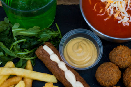 American fast food. A couple of beef and chicken skewers with a delicious peanuts sauce with some fresh salad with tomatoes and crunchy french fries. Delicious meat steaks on a wooden background.の写真素材