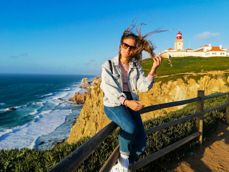 Cabo da Roca, Portugal. Lighthouse and cliffs over Atlantic Ocean, the most westerly point of the European mainland. A beautiful young girl enjoy the placeのeditorial素材