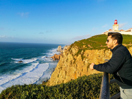 Cabo da Roca, Portugal. Lighthouse and cliffs over Atlantic Ocean, the most westerly point of the European mainland. A young man enjoy the beauty natural place and the sun.のeditorial素材