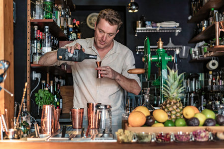 A professional bartender wearing a casual shirt working in a cocktail bar preparing a drink with a smoke machine and a jar, Lisbon, Portugal.のeditorial素材