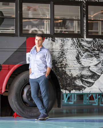 A charming guy posing in front of a stylish urban bus full of graffiti. Lisbon, Portugal