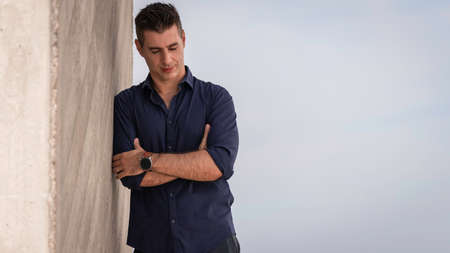Portrait of a beautiful young man posing for a photo session along the tejo riverside in Lisbon, Portugal. Stylish freelance architect relaxing alone near the urban concept building in downtown.の写真素材