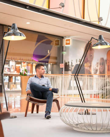 A young joyful business man posing for a portrait photograph inside an empty city mall in the heart...