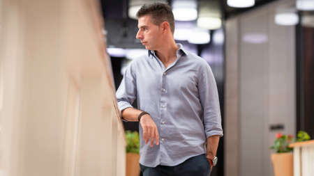 A young joyful business man posing for a portrait photograph inside an empty city mall in the heart of Lisbon, Portugal. Young attractive freelance architect wearing a classy shirt and formal outfitの写真素材