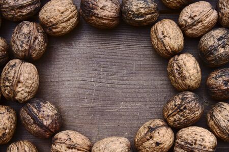 Border with ripe walnuts on a brown wooden boardの写真素材