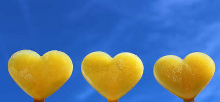 yellow heart shaped ice in front of the skyの写真素材