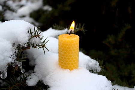 a wax candle with a flame in the snowの写真素材