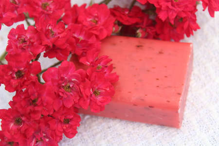 Natural handmade soap with red flowers on a light background. Selective focus.