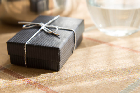 small black jewelry gift box with a silver bow in morning sunlightの写真素材