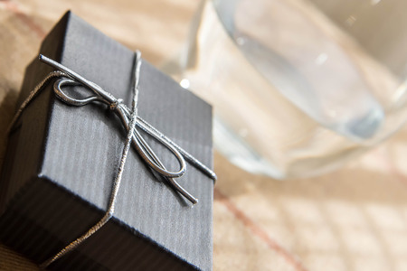 small black jewelry gift box with a silver bow in morning sunlightの写真素材