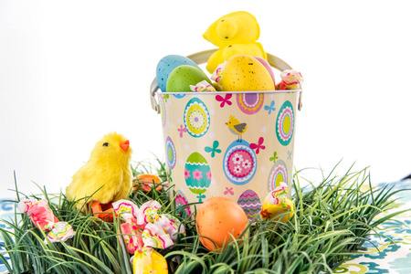 Easter eggs, candy and chicks in bucket on grassの写真素材