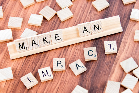 April 5, 2015:  Houston, TX, USA - Scrabble Word Game wood tiles spelling Make An Impactのeditorial素材