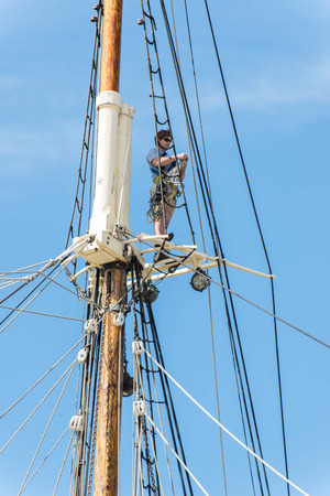 Galveston, TX, USA - October 31, 2014 - man working on a sailboat mast