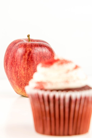 red apple vs red velvet cupcake - snack decision between healthy food or junk foodの写真素材