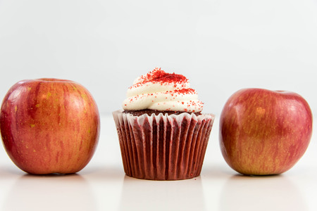 red apple vs red velvet cupcake - snack decision between healthy food or junk foodの写真素材