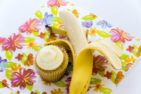 yellow banana vs yellow cupcake - snack decision between healthy food or junk foodの写真素材