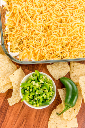 preparation of layered bean dip with jalapenos, sour cream and cheddar cheeseの写真素材