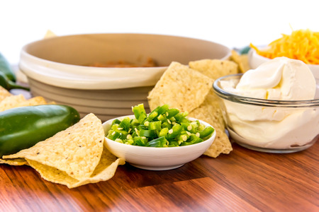 preparation of layered bean dip with jalapenos, sour cream and cheddar cheeseの写真素材