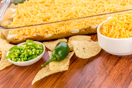 preparation of layered bean dip with jalapenos, sour cream and cheddar cheeseの写真素材