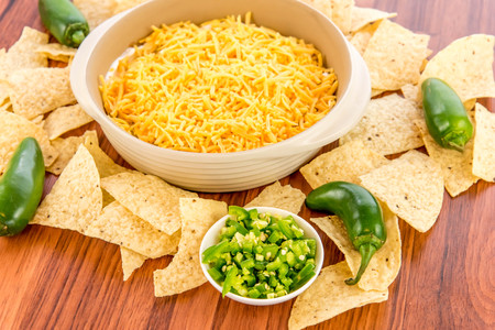 preparation of layered bean dip with jalapenos, sour cream and cheddar cheeseの写真素材
