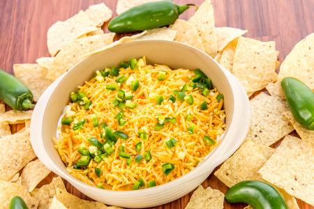 preparation of layered bean dip with jalapenos, sour cream and cheddar cheeseの写真素材