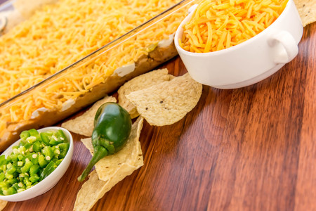 preparation of layered bean dip with jalapenos, sour cream and cheddar cheeseの写真素材
