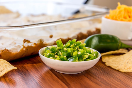 preparation of layered bean dip with jalapenos, sour cream and cheddar cheeseの写真素材