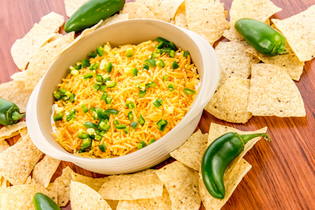 preparation of layered bean dip with jalapenos, sour cream and cheddar cheeseの写真素材