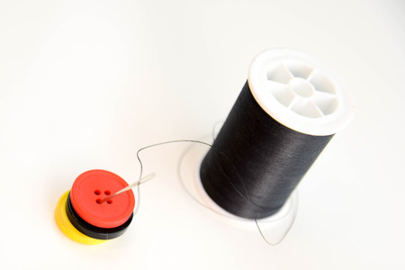 black spool of thread, needle and red, black and yellow buttonsの写真素材