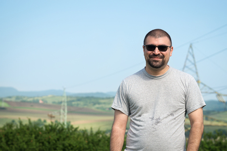 Outdoor summer picture caucasian male with beard wearing t-shirt and sunglasses.の写真素材