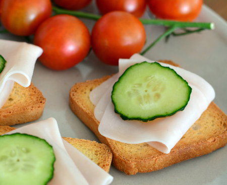 Canape with ham and cucumber and tomato on a white plateの写真素材