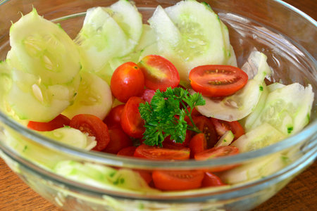 Healthy vegetable salad with cucumber and tomatoes in the glass bowlの写真素材