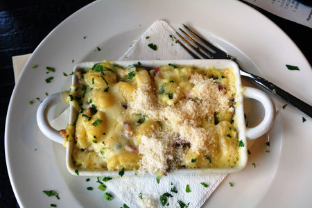Gnocchetti with cheese baked on a white bowl on a tableの写真素材