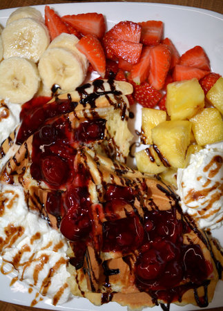 Delicious dessert waffles with fruit and whipped cream and chocolate.の写真素材