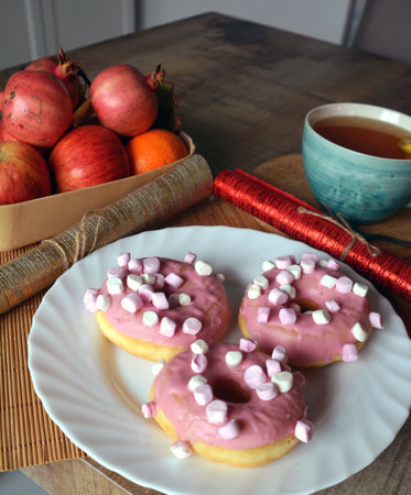 Three donuts with pink icing on a wooden table. Sweet breakfast. Close-up.の写真素材