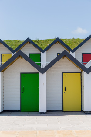 Swanage England  May 2015: Colourful doors of yellow and green with each one being numbered individually of white beach houses on a sunny dayのeditorial素材