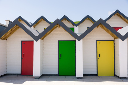 Colourful doors of yellow red and green  with each one being numbered individually of white beach houses on a sunny dayのeditorial素材
