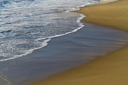 Cropped view of the waves and the sand on the beach on a sunny dayの写真素材