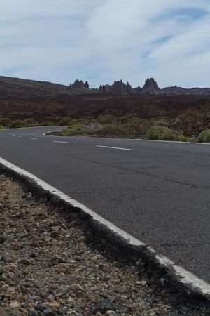 A view from a low angle towards the asphalt road looking at the mountains on a bright sunny dayの写真素材