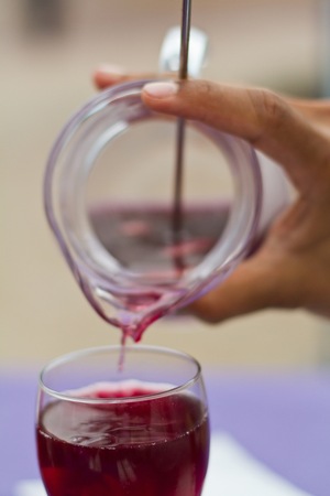 A cropped photo of a hand pouring Sangria in a carafe into a wine glass at the dinner tableの写真素材