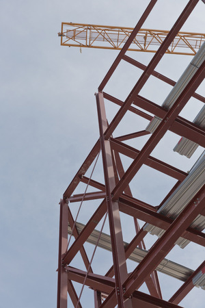 A construction site with steel framing and a yellow construction craneの写真素材