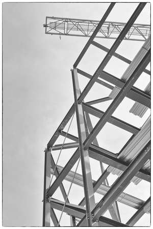 A construction site with steel framing and a yellow construction craneのeditorial素材