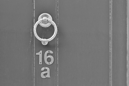 English period wooden front door with ornate iron door knocker. House number position under door knocker. Black and white photoの写真素材