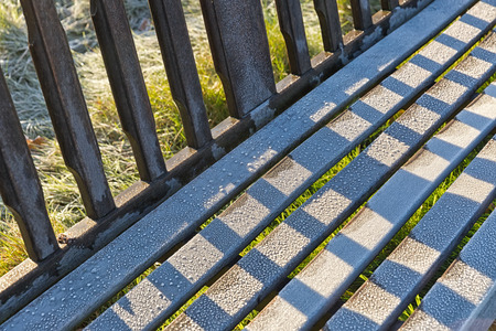 Detail of  frosty garden bench in autumn park landscape